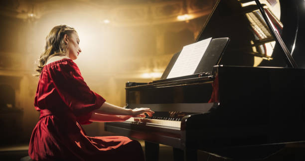 istock Emotional Female Performing Classical Instrumental Music on Stage. Young Musician Using a Grand Piano to Create Beautiful, Melodic Improvisation. Spectators Sitting in a Historic Concert Hall 2190710188
