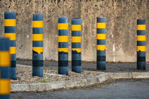istock Black and yellow bollards beside access road and concrete wall 2190710241
