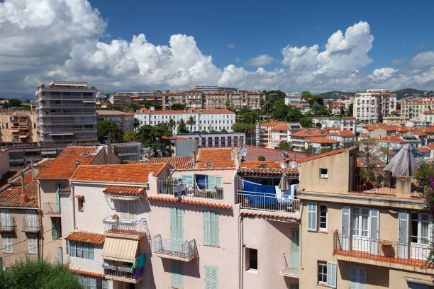 Cannes, France - August 14, 2018: Residential houses with red tiled roofs are under cloudy sky on a sunny day. Aerial view of Cannes old town, France