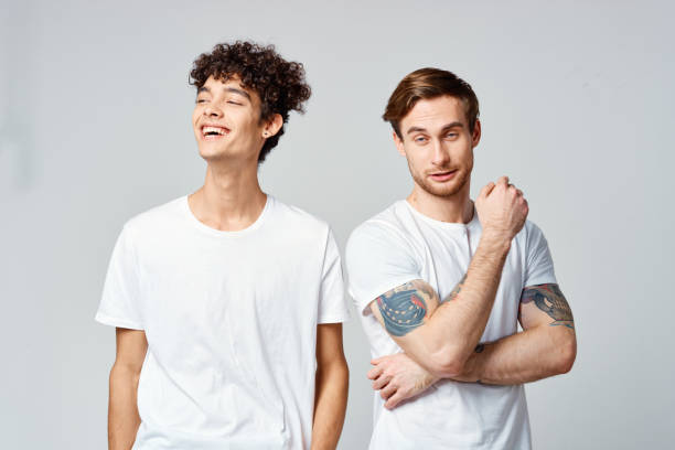 istock Two cheerful friends in white t-shirts stand side by side cropped view 2190716322