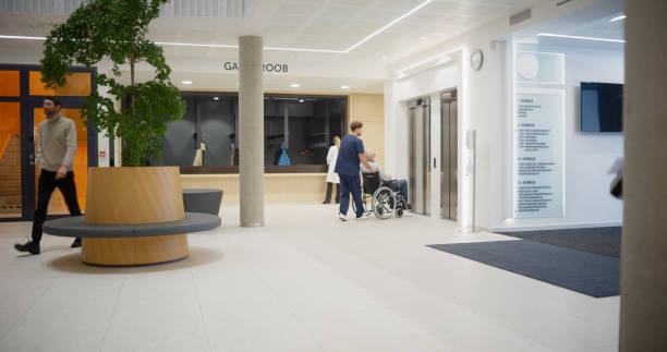 istock Modern Hospital Reception Area is Busy with Activity as Doctors, Patients, and Visitors Interact. Bright Interior with Indoor Plants and Circular Seating Create a Welcoming Healthcare Environment 2190716359