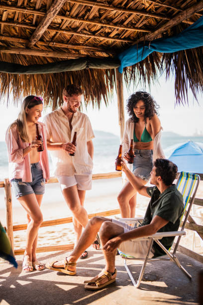 istock Friends talking and drinking beer in restaurant on the beach 2190717072