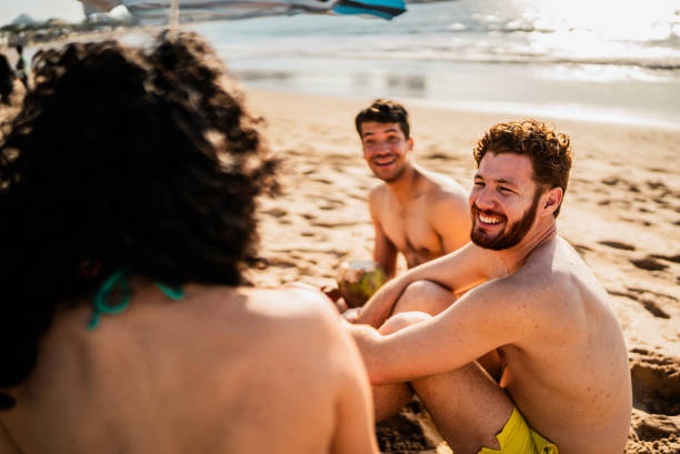 istock Young man talking to friends on the beach 2190717294