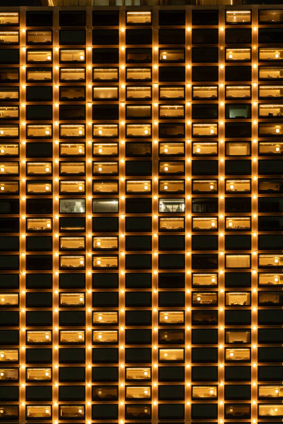 A sleek blue architectural facade frames a bold yellow doorway into a bright, glossy lobby. Blurred pedestrians convey motion and energy, highlighting a dynamic urban corporate atmosphere.