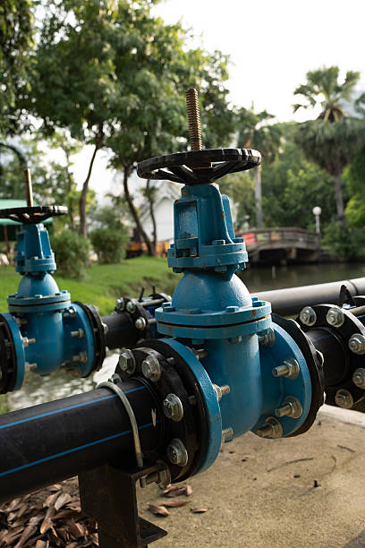 istock blue industrial valve on pipeline near serene waterway, surrounded by greenery 2190718640