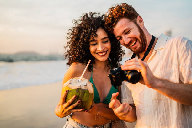 Young couple talking and looking photos on camera on the beach