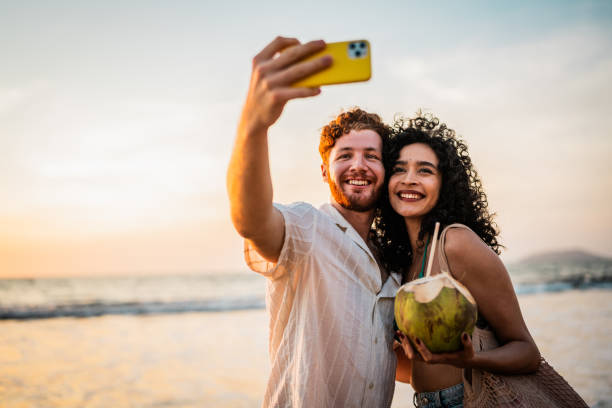 istock Young couple using mobile phone and talking on the beach 2190718765