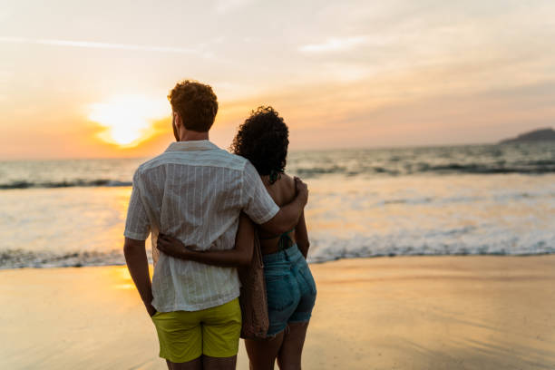 istock Young couple relaxing looking at view on the beach 2190718796