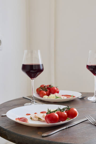 A beautifully set dining table with exquisite red wine and ripe tomatoes, ideal for romantic dinners