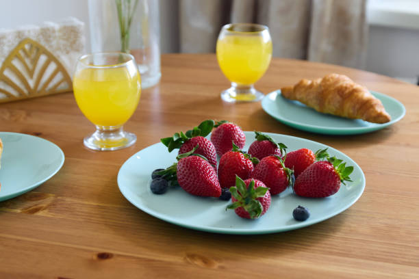 A bright and colorful breakfast spread featuring an array of strawberries, blueberries, and refreshing juices
