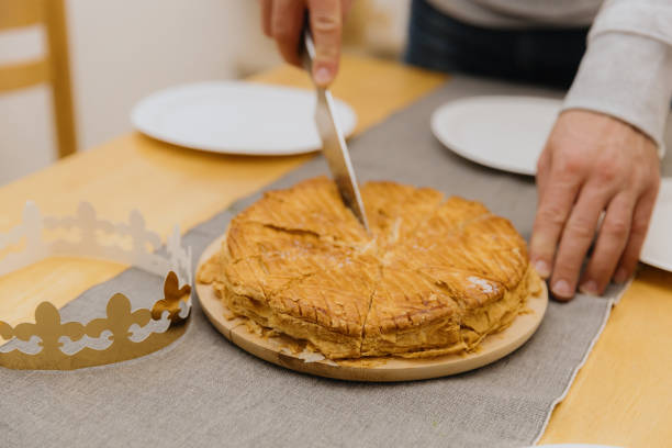 istock A young man cuts a royal galette at the table. 2190723668