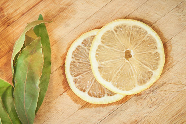 Horizontal composition with top view of two lemon slices and bay leaves on a wooden cutting board