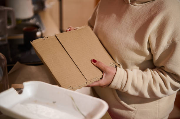 istock Person holding cardboard for recycling in a kitchen environment 2190729409