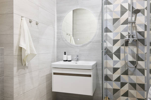 A modern bathroom with stylish geometric tiles, a beautiful circular mirror, functional and elegant