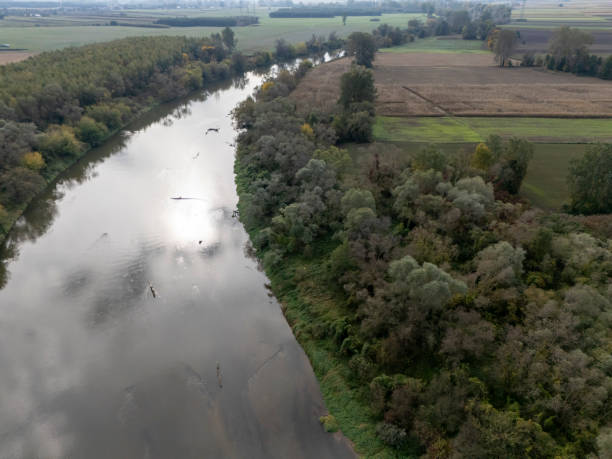 istock Aerial view of a serene river surrounded by lush greenery and agricultural fields, creating a picturesque landscape 2190733770