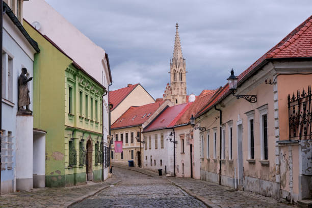 A quiet cobblestone street in Bratislava with the ornate spire from the Church of Annunciation in the backround.