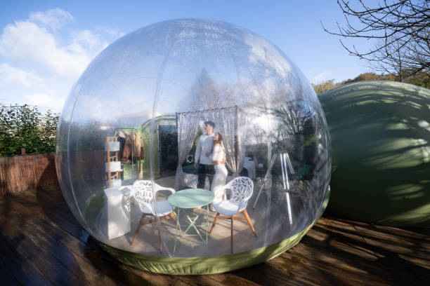 istock Newlyweds hugging inside transparent bubble accommodation, sharing intimate moment surrounded by minimalist interior, wooden terrace gleaming under bright sunlight 2190738272