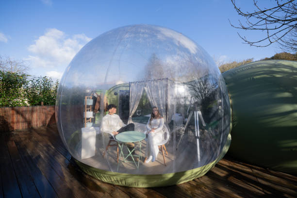 istock Romantic travelers relaxing inside transparent geodesic accommodation, embracing scenic wilderness landscape and intimate moment of connection 2190738275