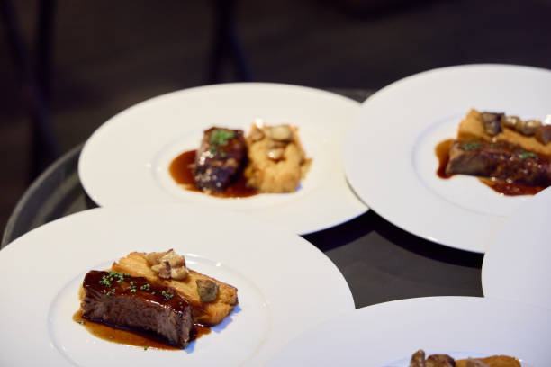 A lively background of people enjoying a meal with a plate of beef tenerdloin in the foreground.
