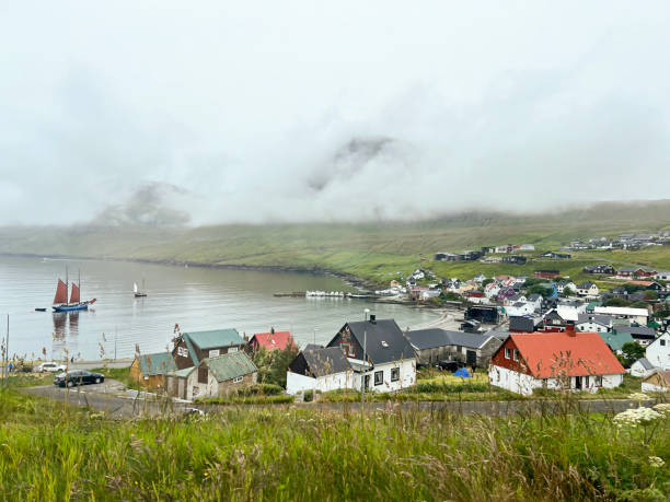 Low clouds and fog hang over the mountains and the historic village of Syðrugøta, Eysturoy, Faroe Islands. Syðrugøta is known for the G! festival and its fishing industry.