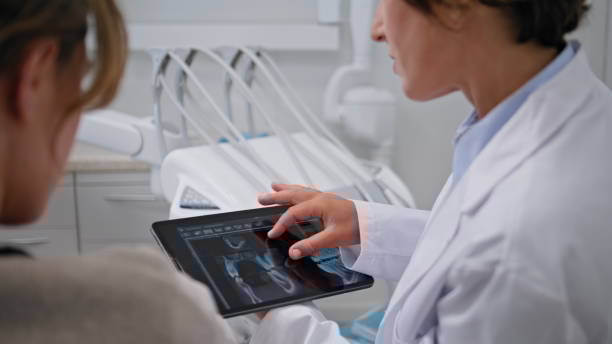 Dentist showing dental x-rays on tablet at stomatology consultation closeup. Dentist showing dental x-rays on tablet at stomatology consultation closeup. Woman stomatologist providing detailed analysis of oral health with digital tools. Female patient listen medical explaining tablet pc and digital hospital tools stock pictures, royalty-free photos & images