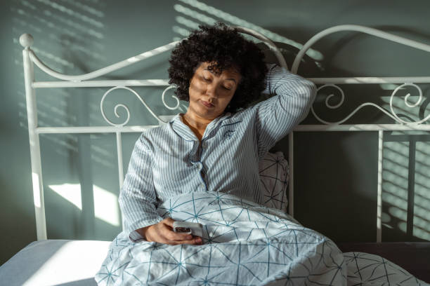 istock Mature woman relaxing in bed while using her phone in the morning 2190744709
