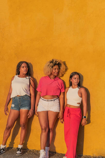 istock Three young women leaning against a vibrant yellow wall 2190747540