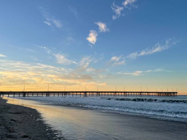 istock Scattered clouds with blue yellow sky and pier at the beach. 2190748887