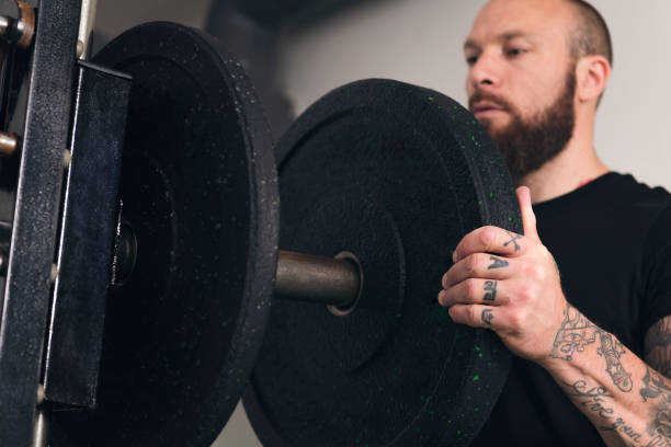 sportsman putting weight plate on gym machine