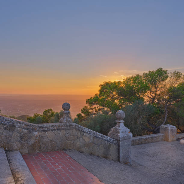 Beautiful sunset landscape in Mallorca, Spain, showcasing trees, historic architecture, and tranquil nature, conveying a serene and picturesque environment.