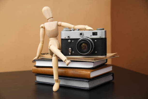 Vintage camera, notepads and wooden man on table on beige background