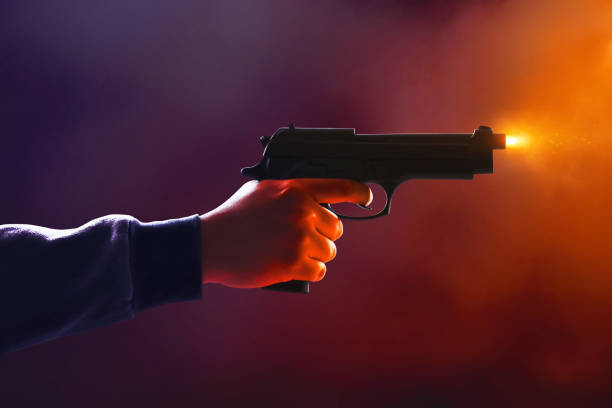 istock Hooded man holding a gun on dark smoke background 2190775284