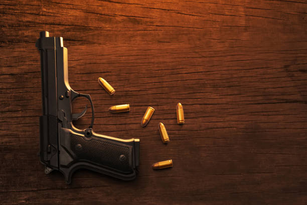 istock Top view gun and bullets on dark brown wooden table texture 2190775985