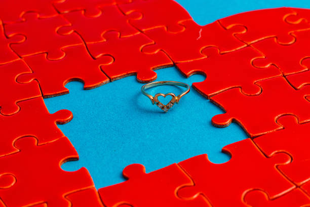 Love concept. Broken heart puzzle with wedding ring, on light blue background High quality photo.