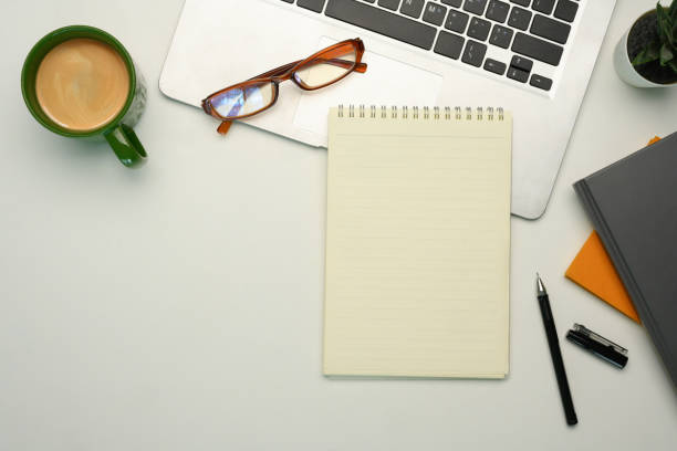 istock Flat lay of workspace with laptop, notebook, glasses and a coffee cup on white background 2190778284