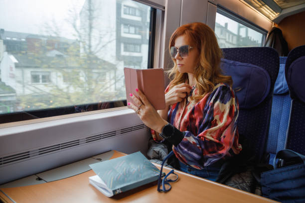 istock Beautiful woman with sunglasses riding train by day, looking at smart phone, using it as a mirror 2190780326