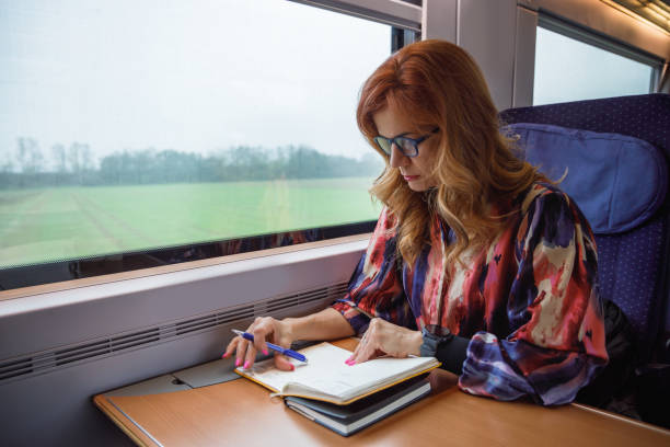 istock Beautiful woman with eyeglasses riding train by day, going to work and reading her notes 2190780382