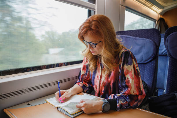 istock Beautiful woman with eyeglasses riding train by day, going to work and taking notes 2190780383
