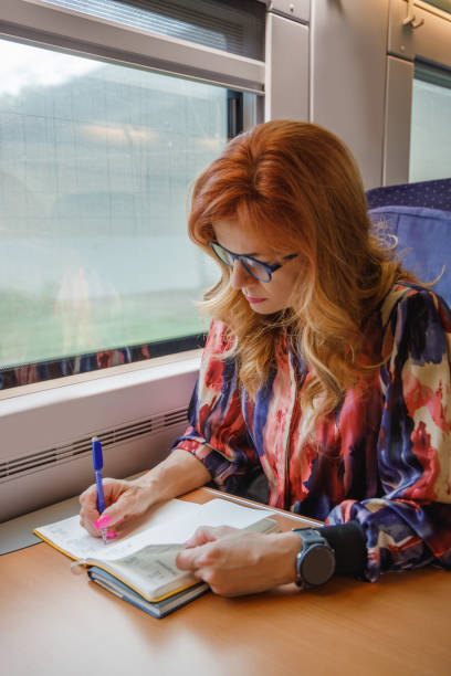 istock Beautiful woman with eyeglasses riding intercity train by day, going to work and taking notes 2190780386