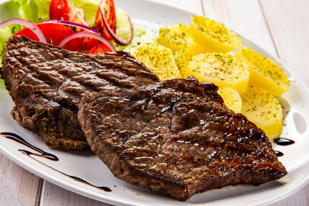 istock Seared beef steaks with boiled potatoes and fresh vegetable  on wooden table 2190780558