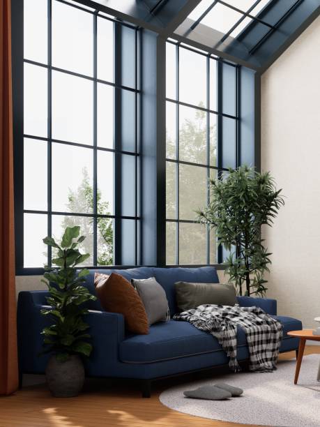 istock 3D rendering of A cozy living room with large windows, a blue sofa adorned with pillows, a blanket, and indoor plants, creating a bright and inviting atmosphere. 2190780914