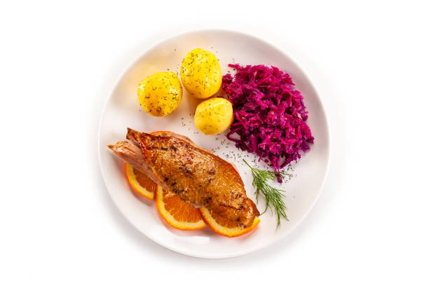 Roast duck breast with boiled potatoes and pickled red cabbage on white background