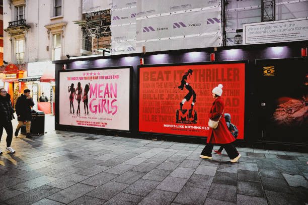 Central London West End Theatre District mean girls at savoy theatre and michael jackson musical UK Central London, England, United Kingdom, GB. 19th December 2024. A street view captured in the evening during the Christmas holiday season in central London, UK. Pedestrians walk on the street. MJ The Musical poster seen in central London, will be shown at the Prince Edward Theatre next year. cirque de soleil stock pictures, royalty-free photos & images
