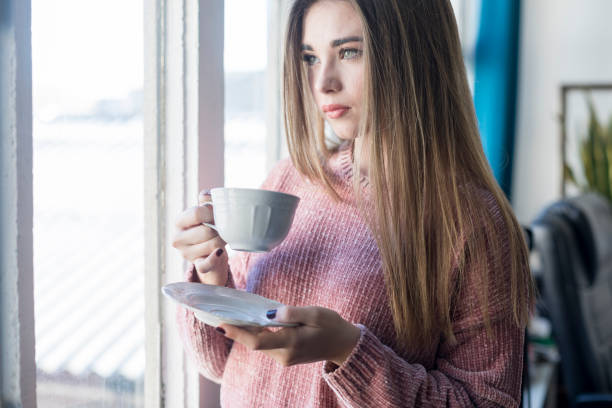 istock Woman enjoying tea by the window in a bright indoor space. 2190782756