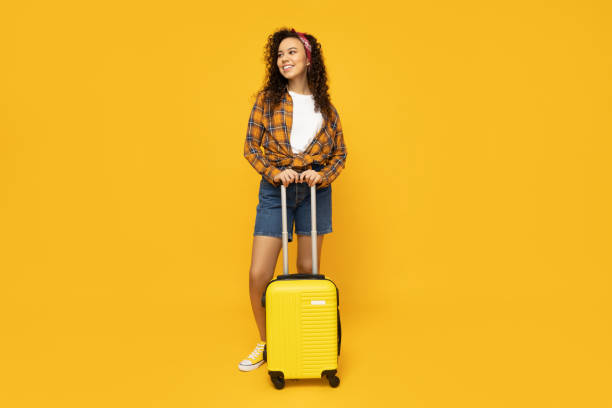 istock Young woman with suitcase on yellow background 2190782961