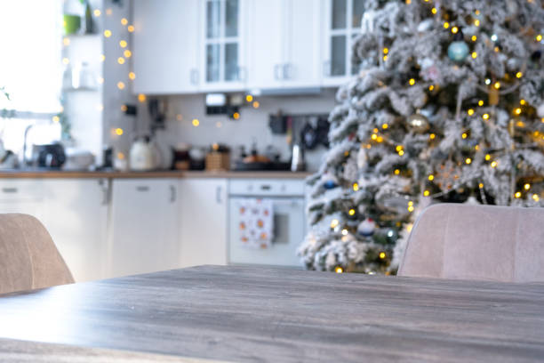 istock Grey Wooden empty table to demonstrate product with space for text with upholstered chairs in white kitchen, modern interior with Christmas tree and fairy lights. New Year, Christmas mood, cozy home. 2190783203