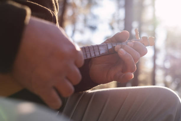 A young man is playing a traditional Turkish musical instrument, the Cura, in the forest.
