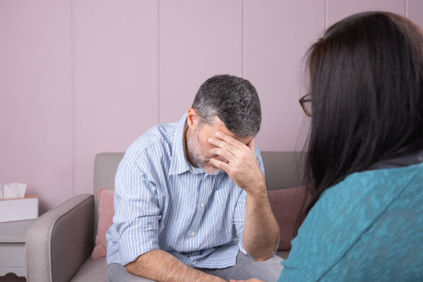 istock A man in a therapy session hides his face with one hand, while his psychotherapist, with his back turned, accompanies him in a quiet environment 2190786654