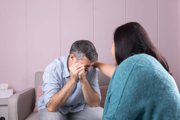 istock A man in psychological consultation cries with his hands covering his face, while the psychotherapist, with her back turned, accompanies him in a warm and professional environment 2190786663
