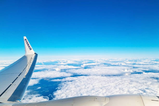 Barcelona, Spain, September 29, 2024: A tranquil aerial scene featuring the wing of a ryanair airplane, soaring above a vast expanse of fluffy white clouds under a clear blue sky. perfect for travel, aviation, and journey-themed projects.